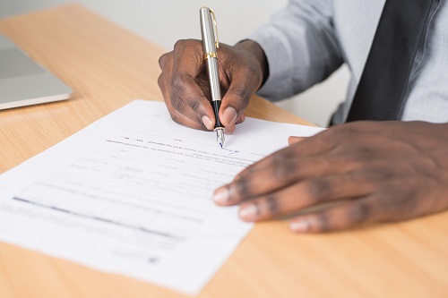 Photo of mans hands signing a form