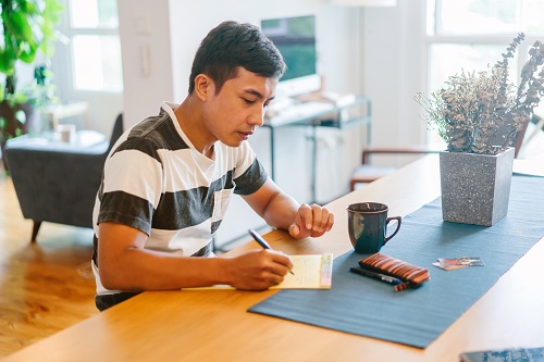 Photo of young man writing on notepad